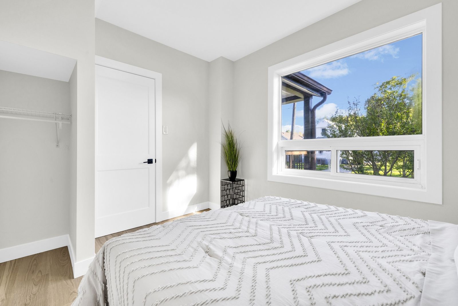 Bedroom with a bed, a closet and a window looking out to the front porch.