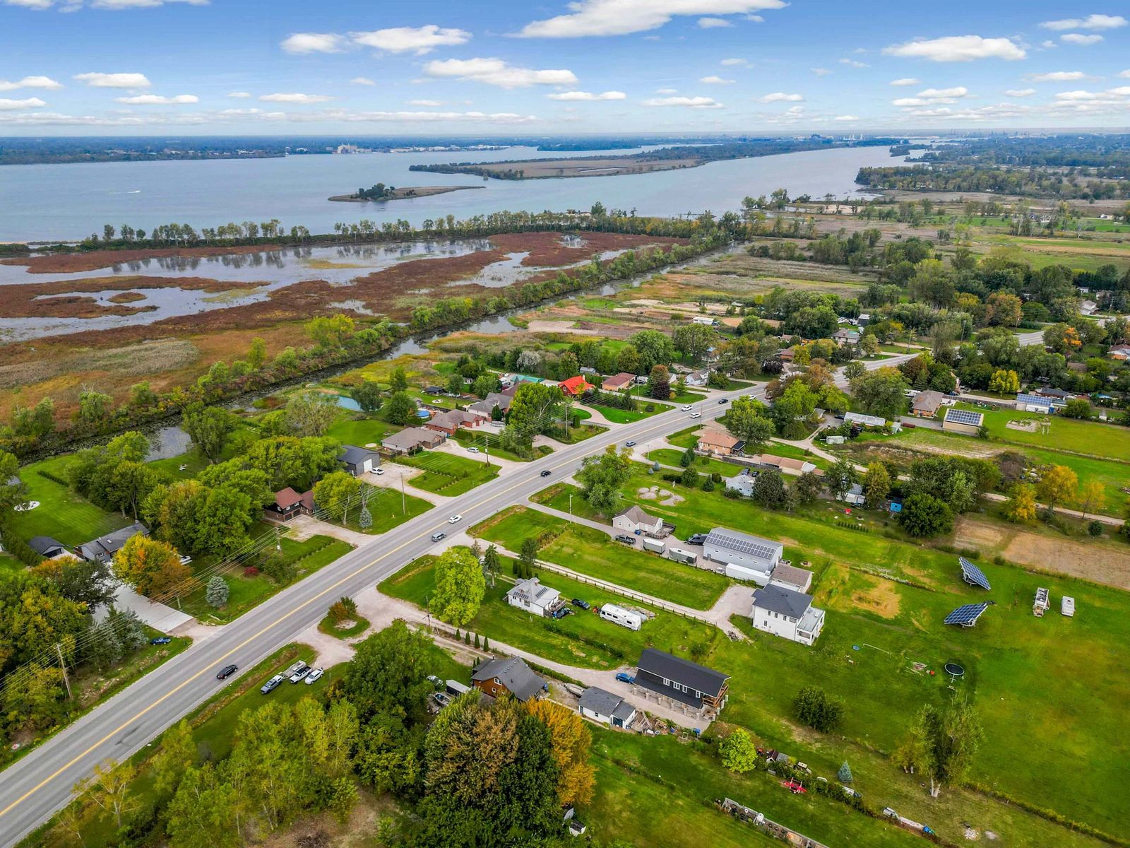 Wide aerial view of the river, canal, marshland and properties along the road.