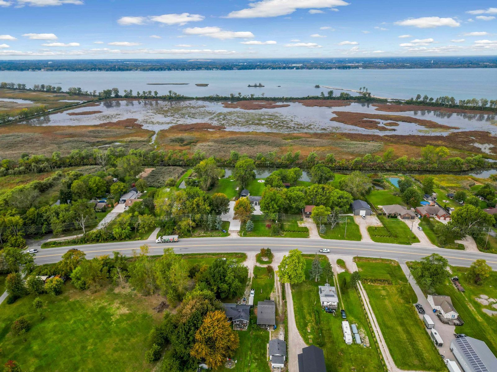 Aerial view of the river, the canal and marshland, with houses along the road.