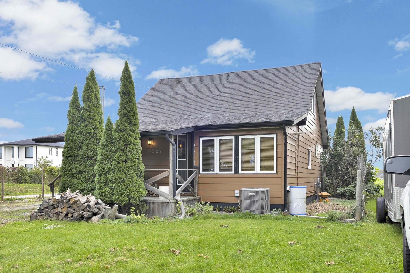 Front of the house with the covered porch, evergreens and lawn.