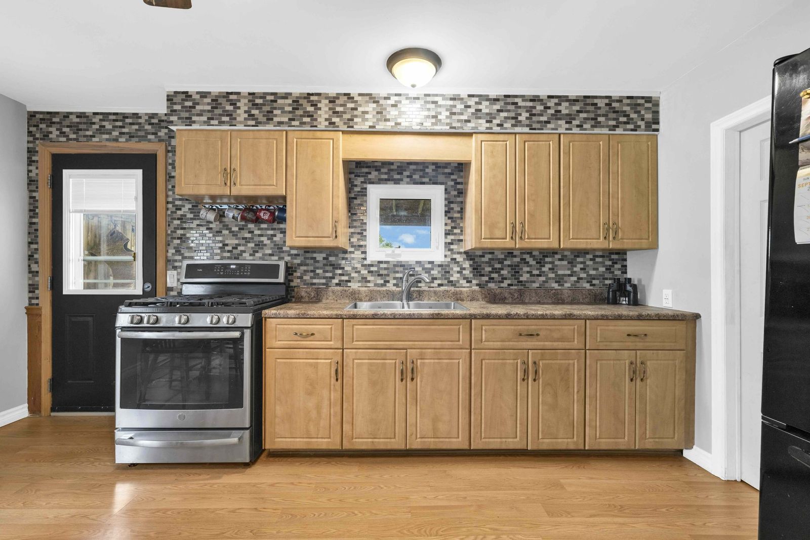 Kitchen with wood cabinets, gas range, tile backsplash and a window over the sink.