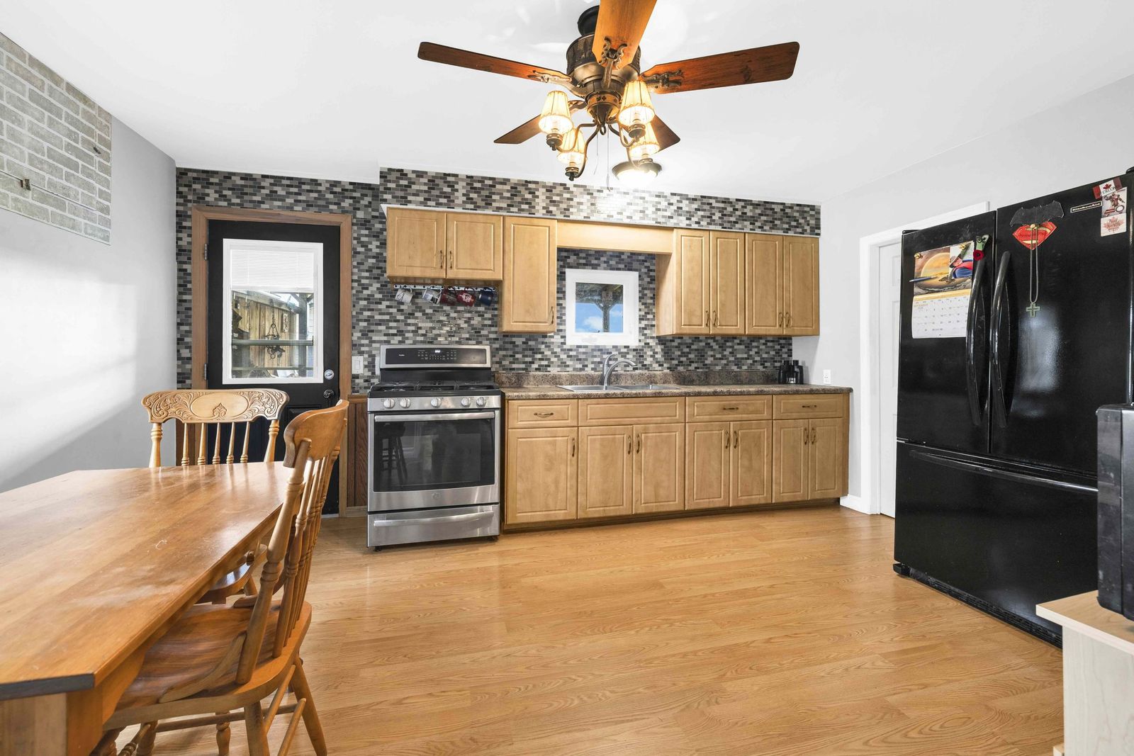 Kitchen with wood cabinets, stove, refrigerator and a dining table.