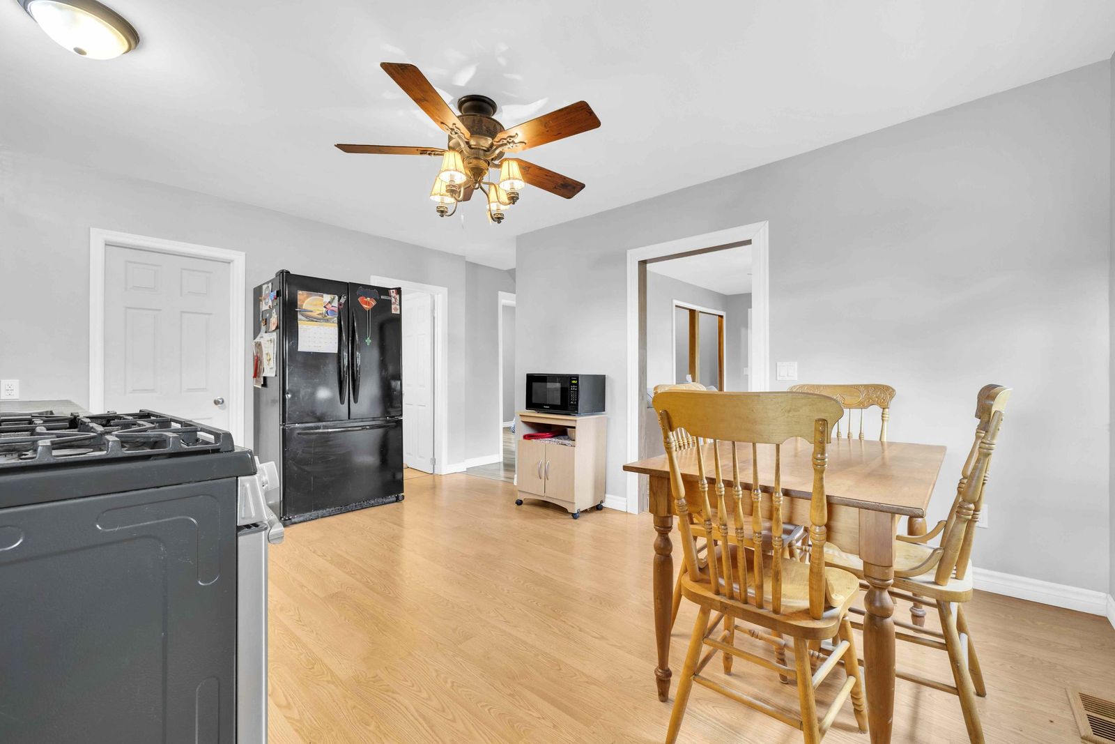 Kitchen dining area with a wooden table and chairs, refrigerator and stove.