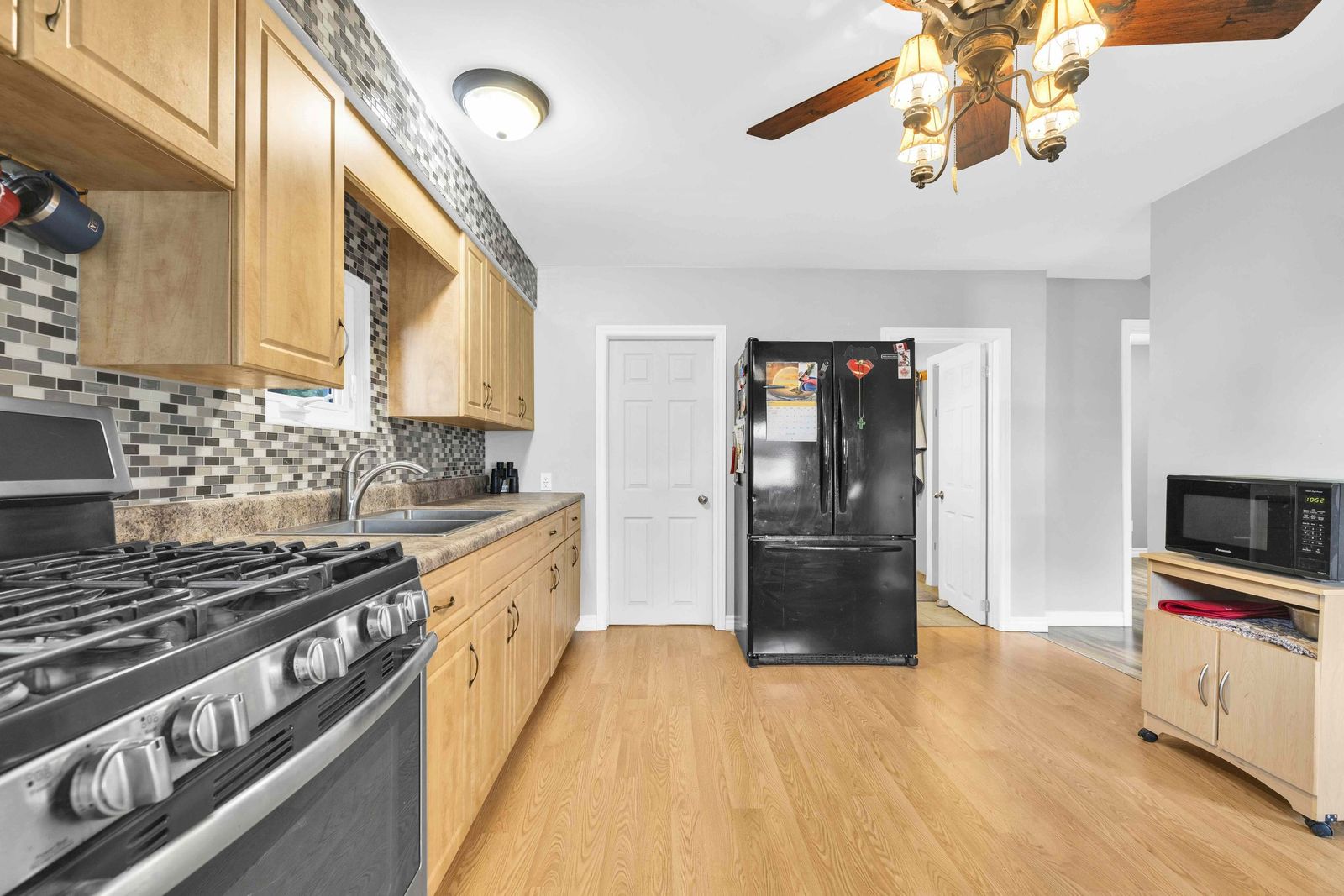 Kitchen with wood cabinets, gas range, tile backsplash and a black refrigerator.