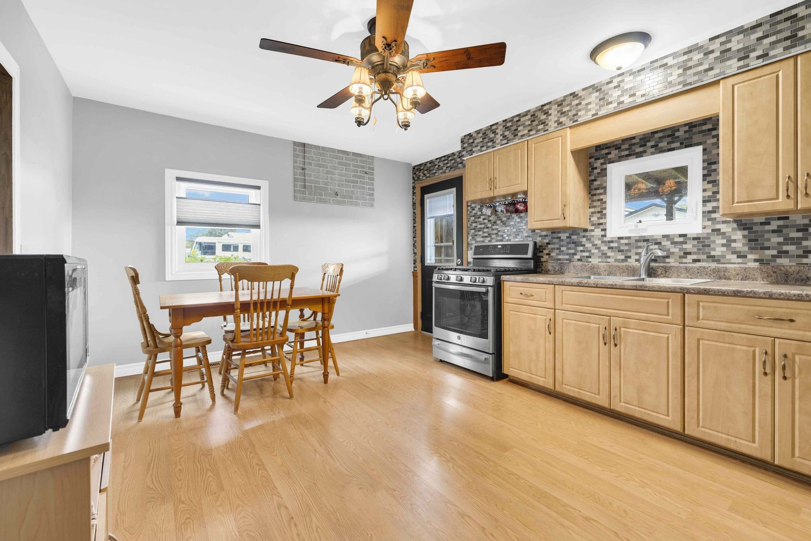 Kitchen with wood cabinets, stainless steel stove, tile backsplash and a dining table.