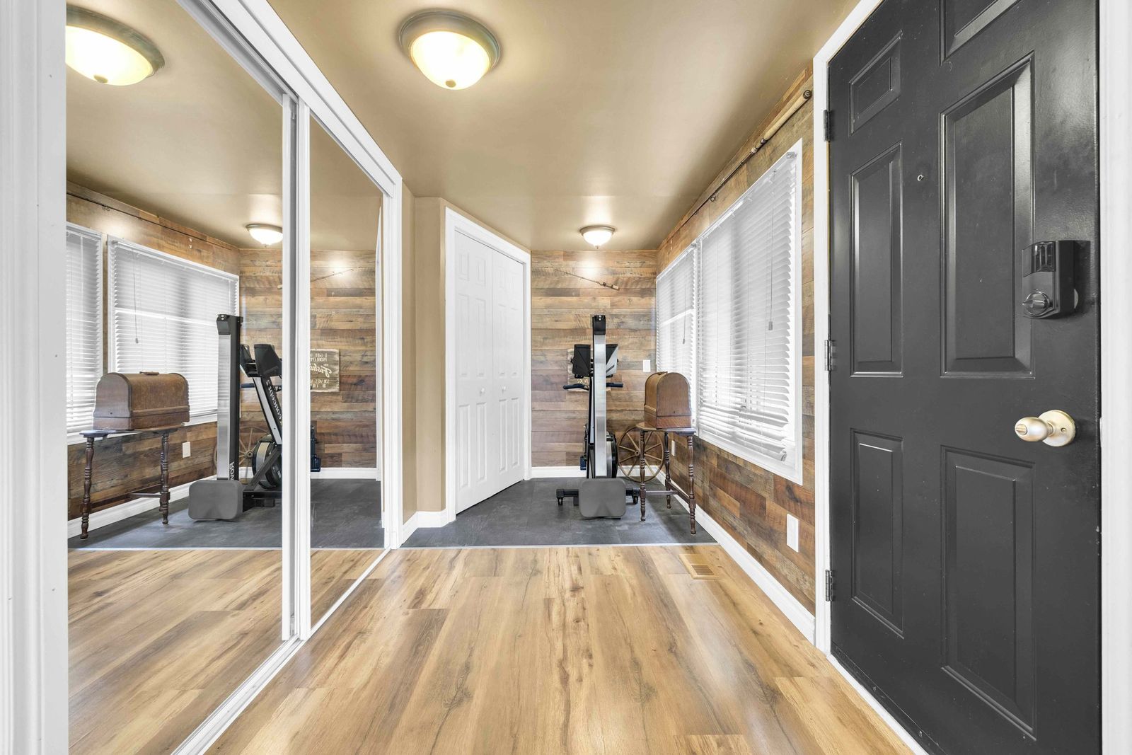 Entry with wood-panel walls, mirrored closet doors and the front door.