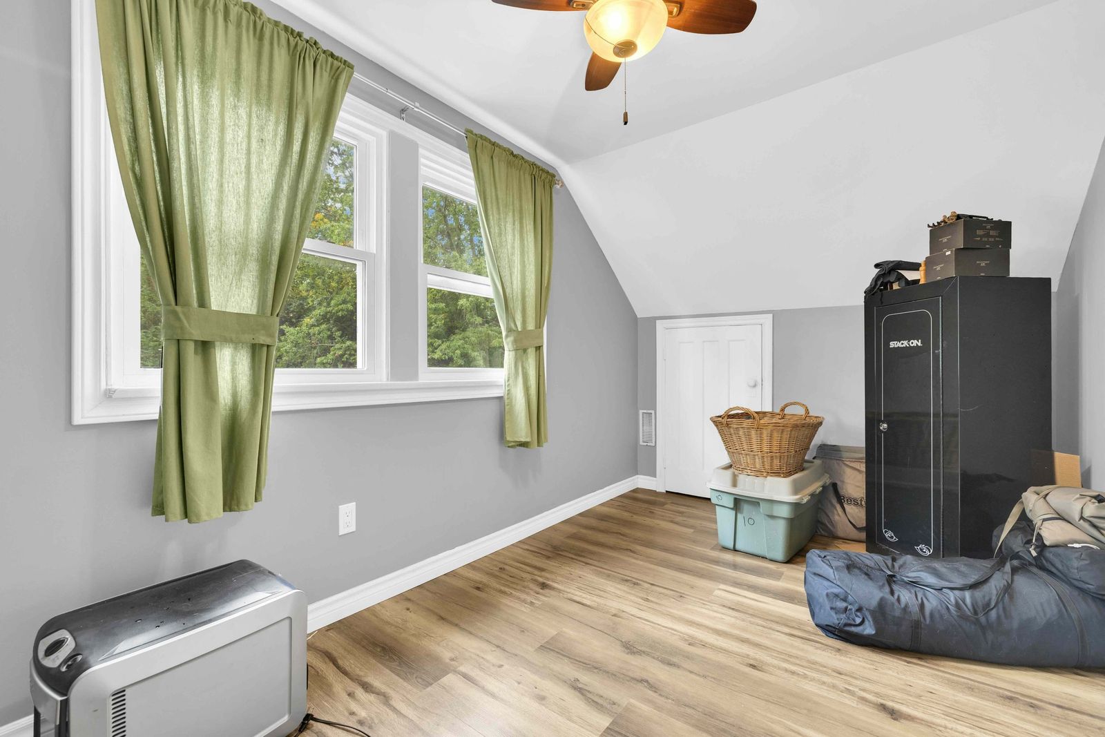Bedroom with a sloped ceiling, ceiling fan and storage cabinet.