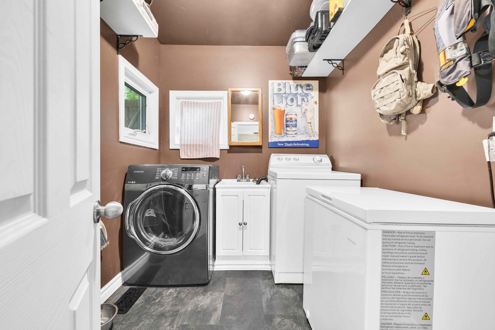 Laundry room with washer, dryer, utility sink cabinet and freezer.