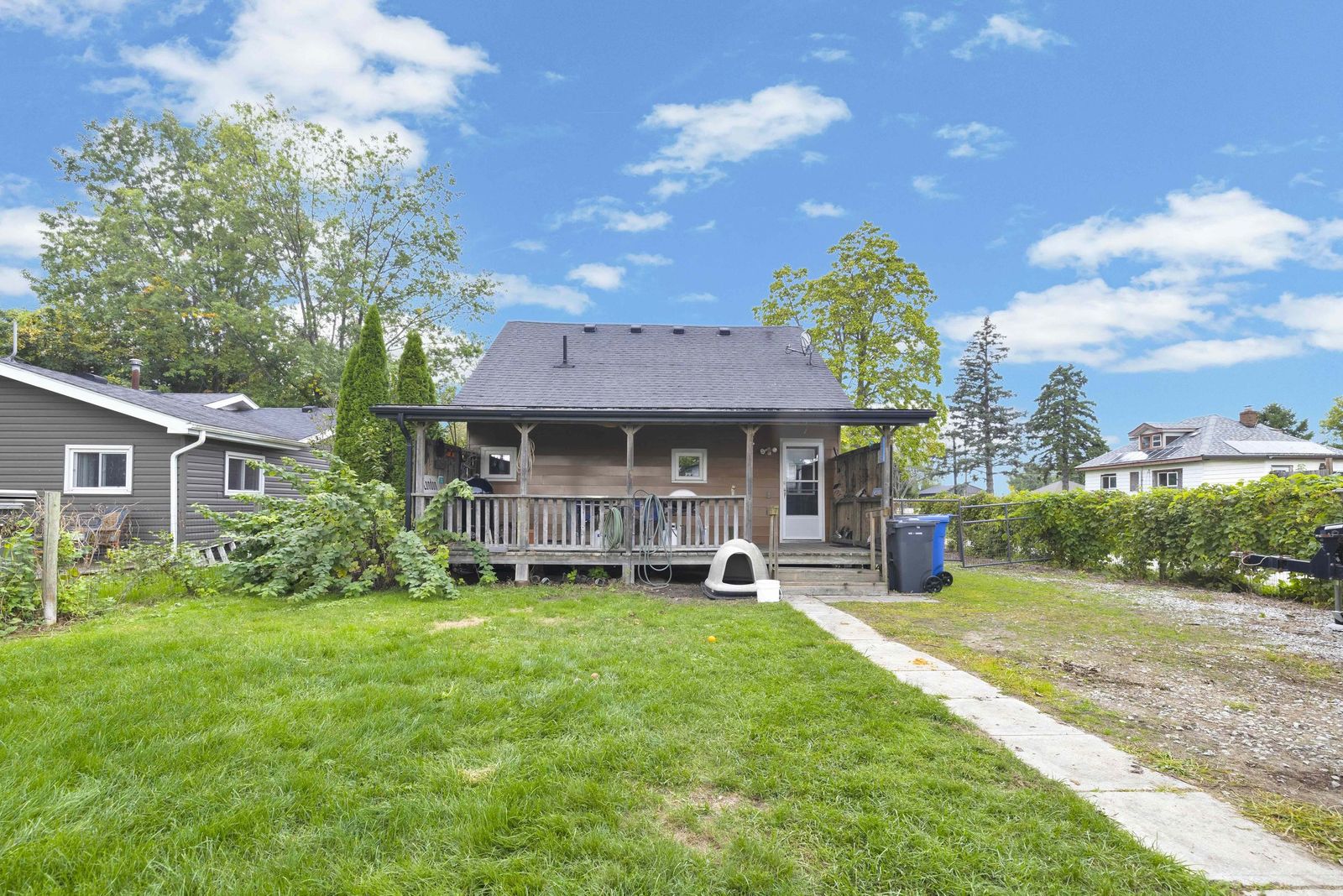 Back of the house with the covered porch, lawn and a stone path.