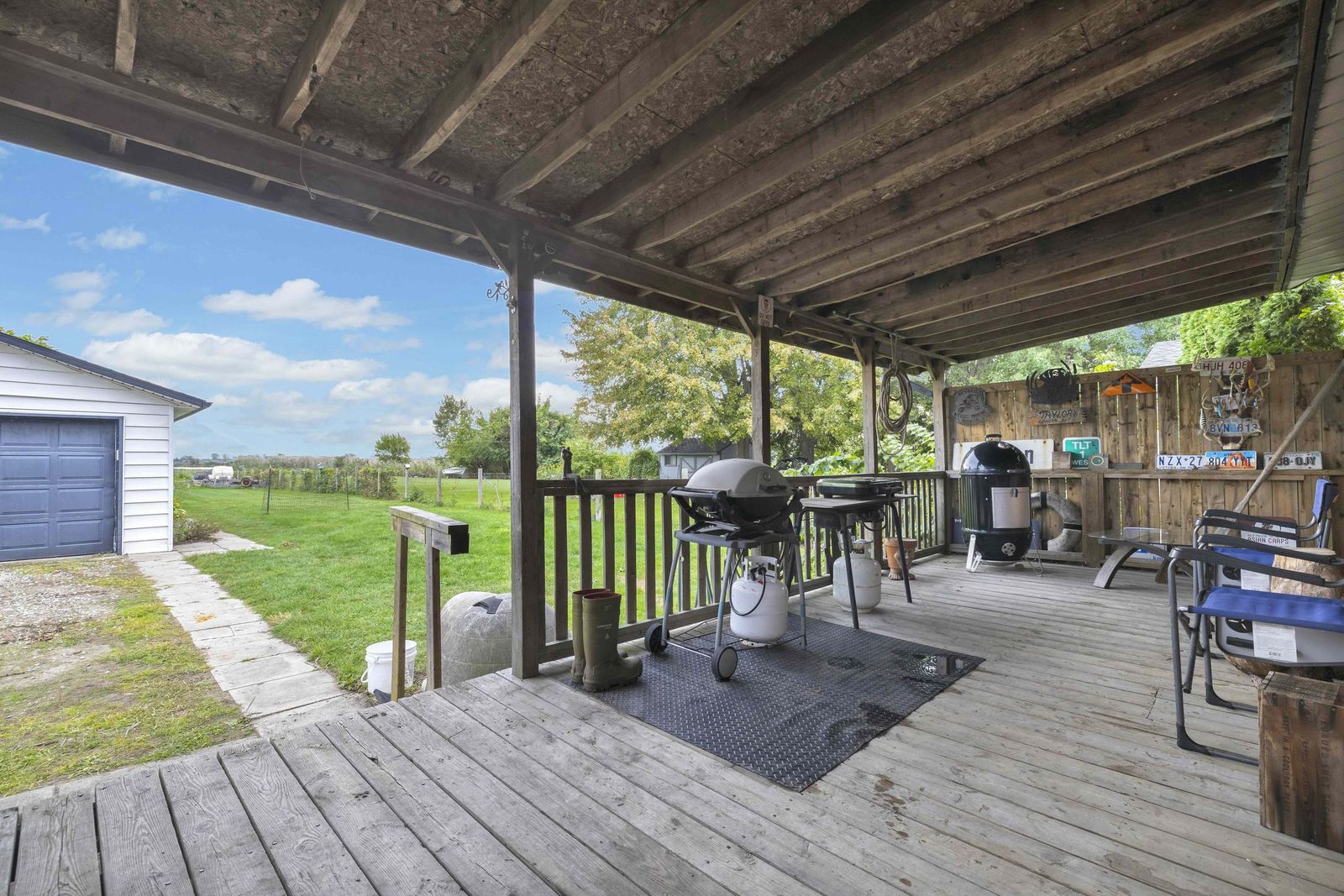 Covered back porch with a barbecue and seating, looking out to the yard.