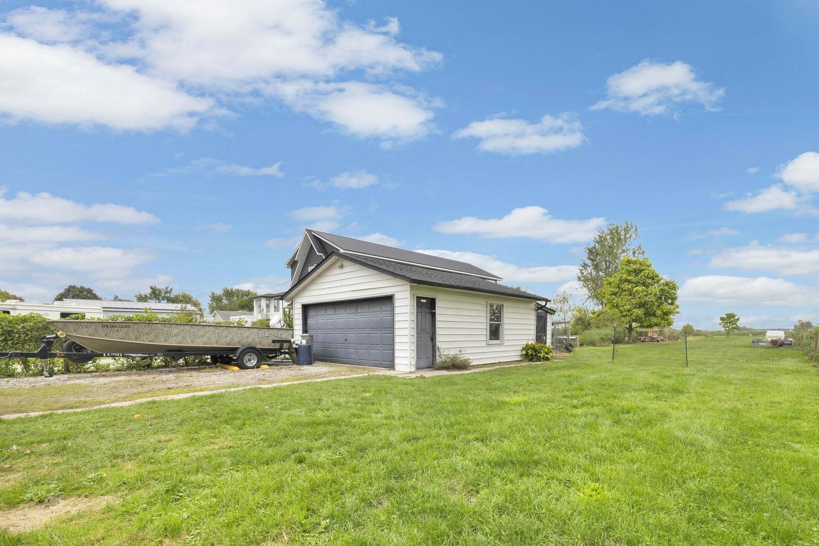 Detached garage with a boat on a trailer beside it.