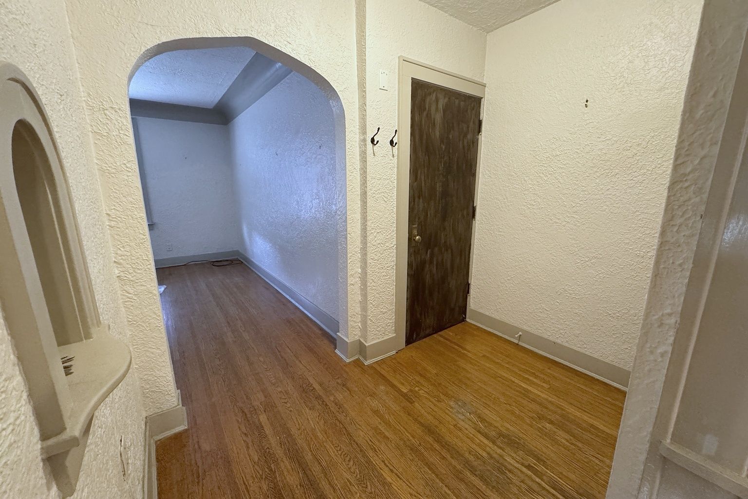 Hallway with an arched opening, a wood floor and a dark wooden door.