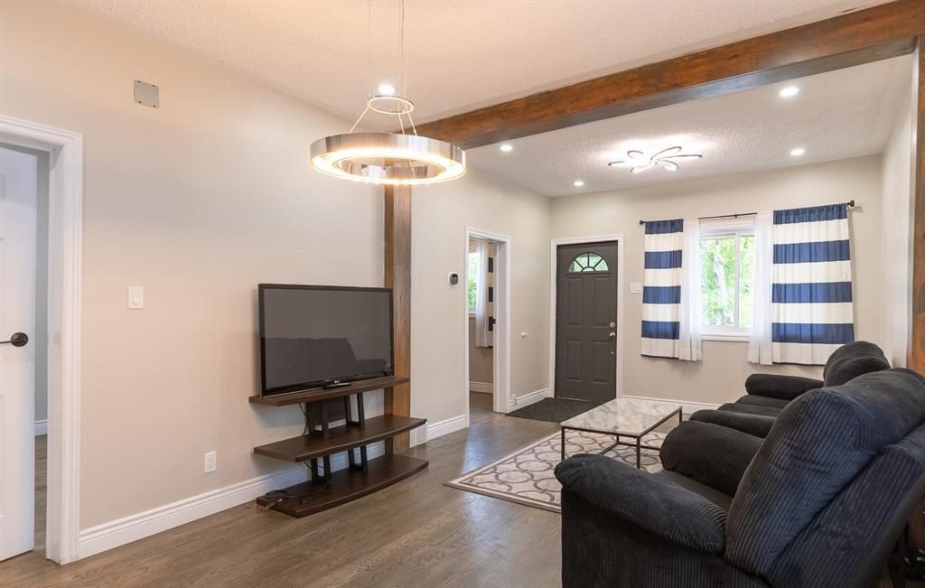 Living room with a hanging light fixture, a television and the front door beyond.