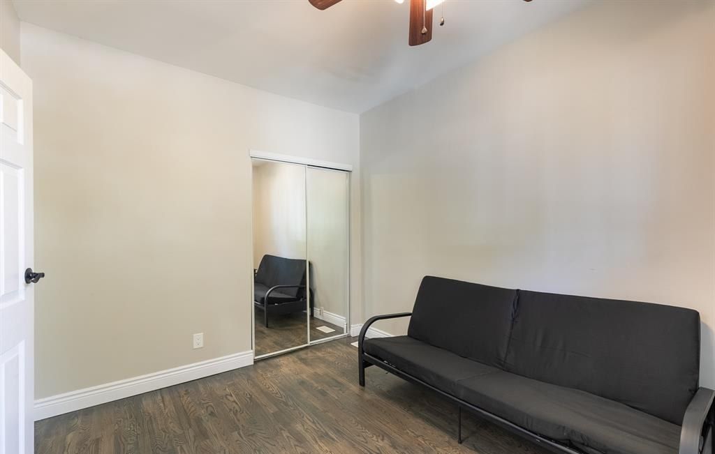 Room with a futon, a mirrored closet door and a window.