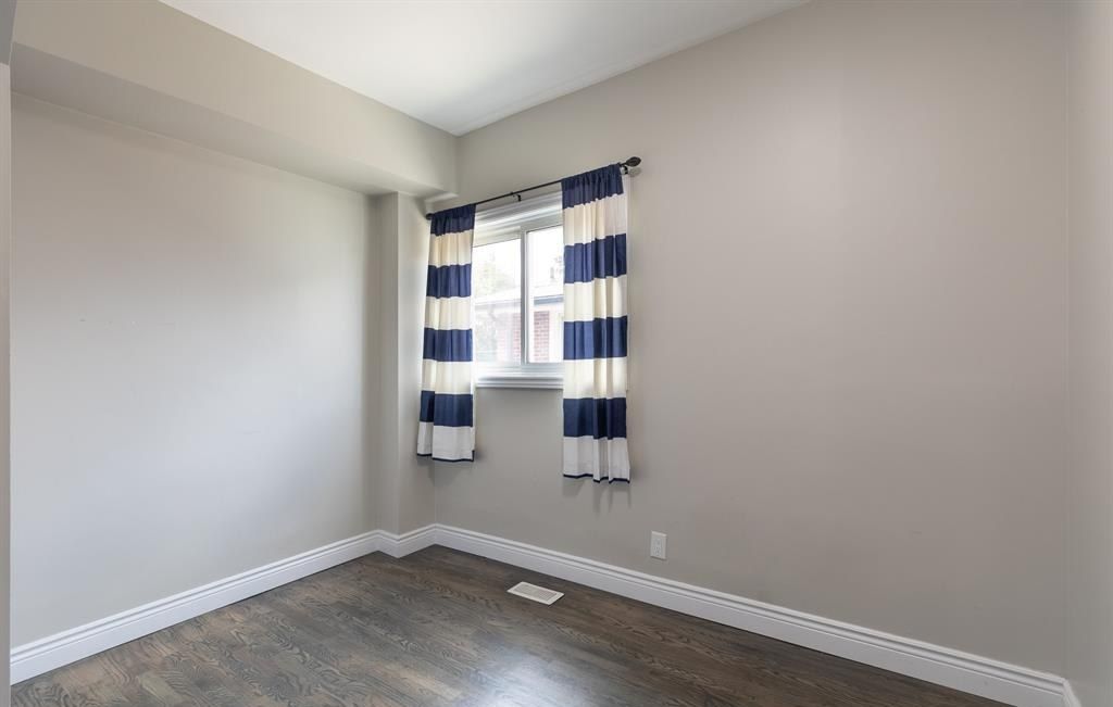 Empty room with grey walls and a curtained window.
