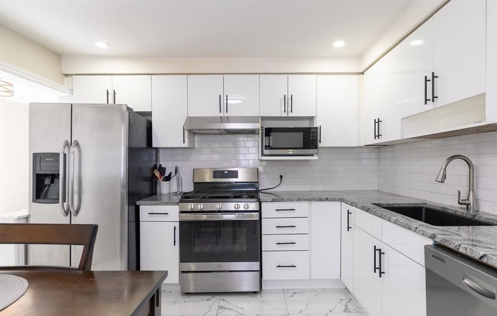 Kitchen with white cabinets, a stainless refrigerator and a gas range.