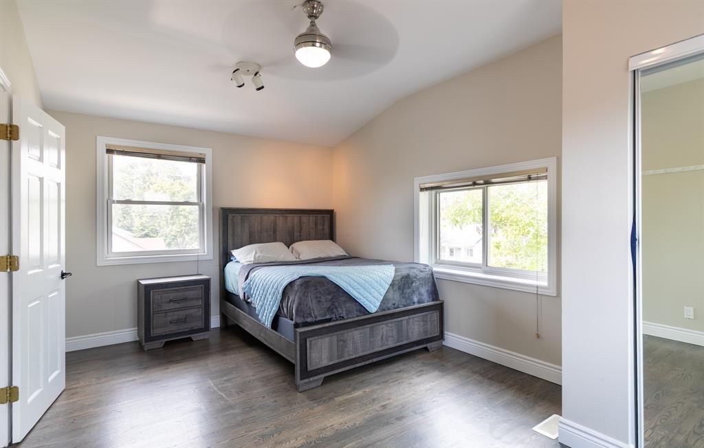 Bedroom with a bed, two windows and a ceiling fan.