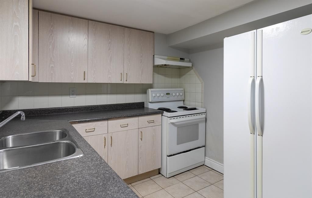 Kitchen with wood cabinets, a range, a refrigerator and a double sink.