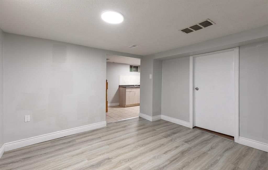 Empty room with a doorway through to a kitchen.