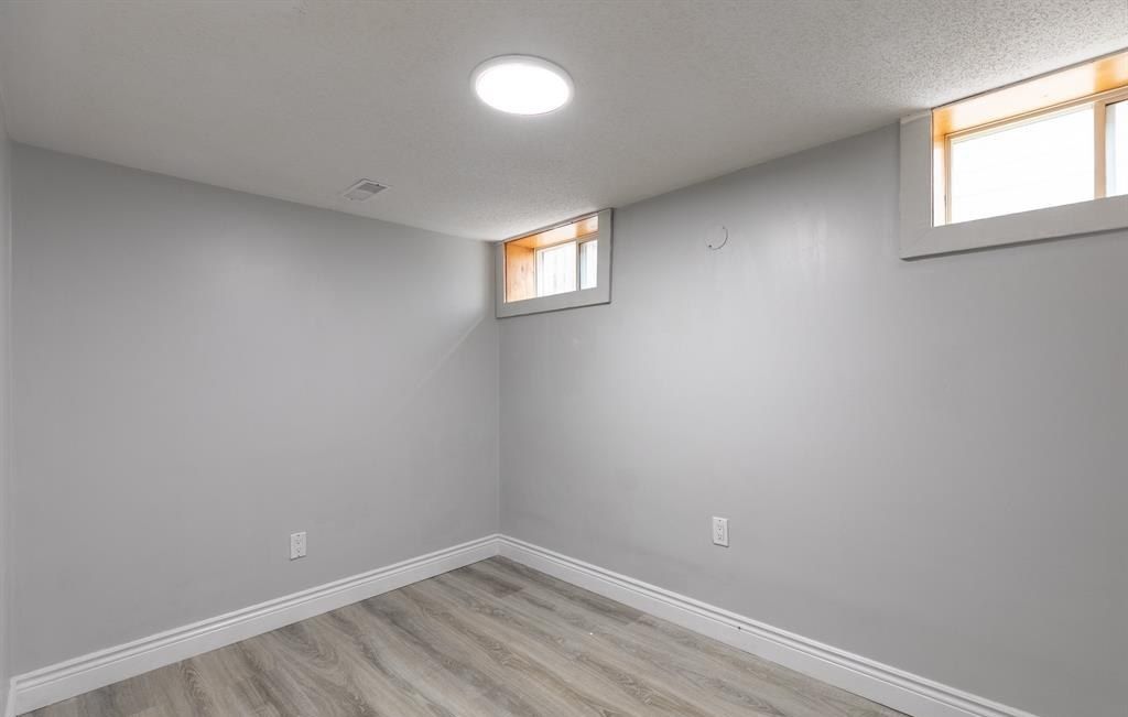 Empty room with grey walls and two small high windows.