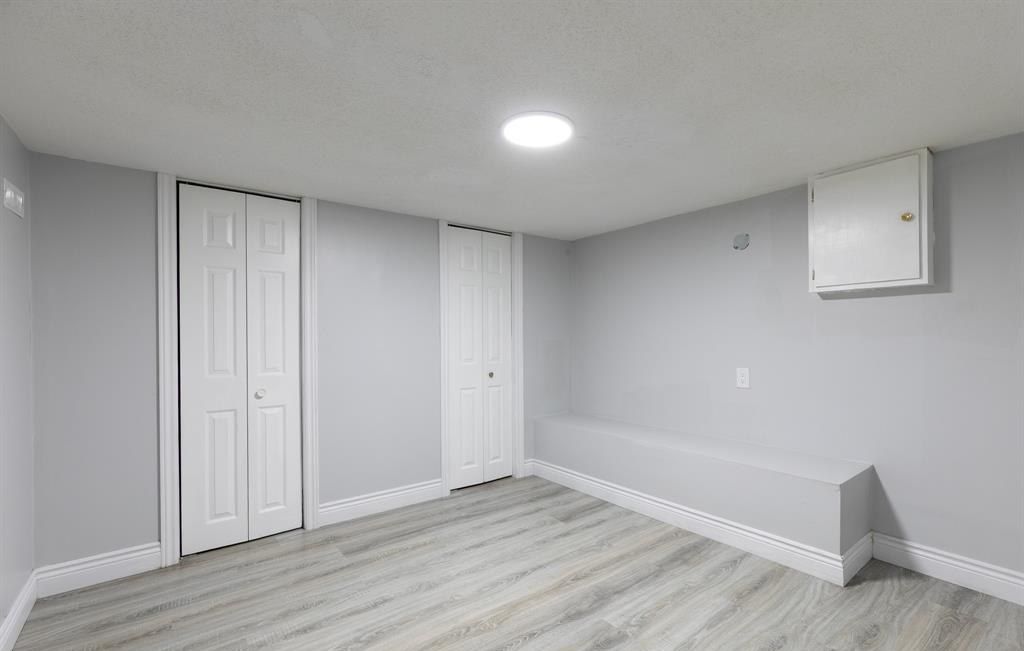 Empty room with two closet doors and a small high window.